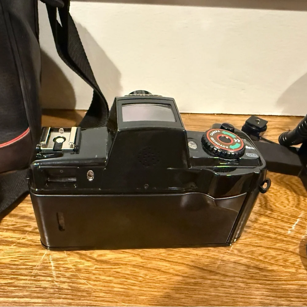 Vintage Canon camera with a flash attachment and carrying case.